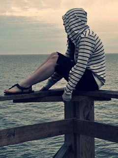 Menina contemplativa à beira-mar