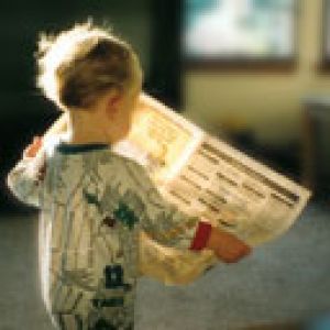 Criança lendo um jornal