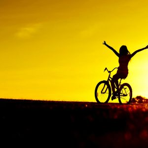 Menina Andando de Bicicleta ao Pôr do Sol